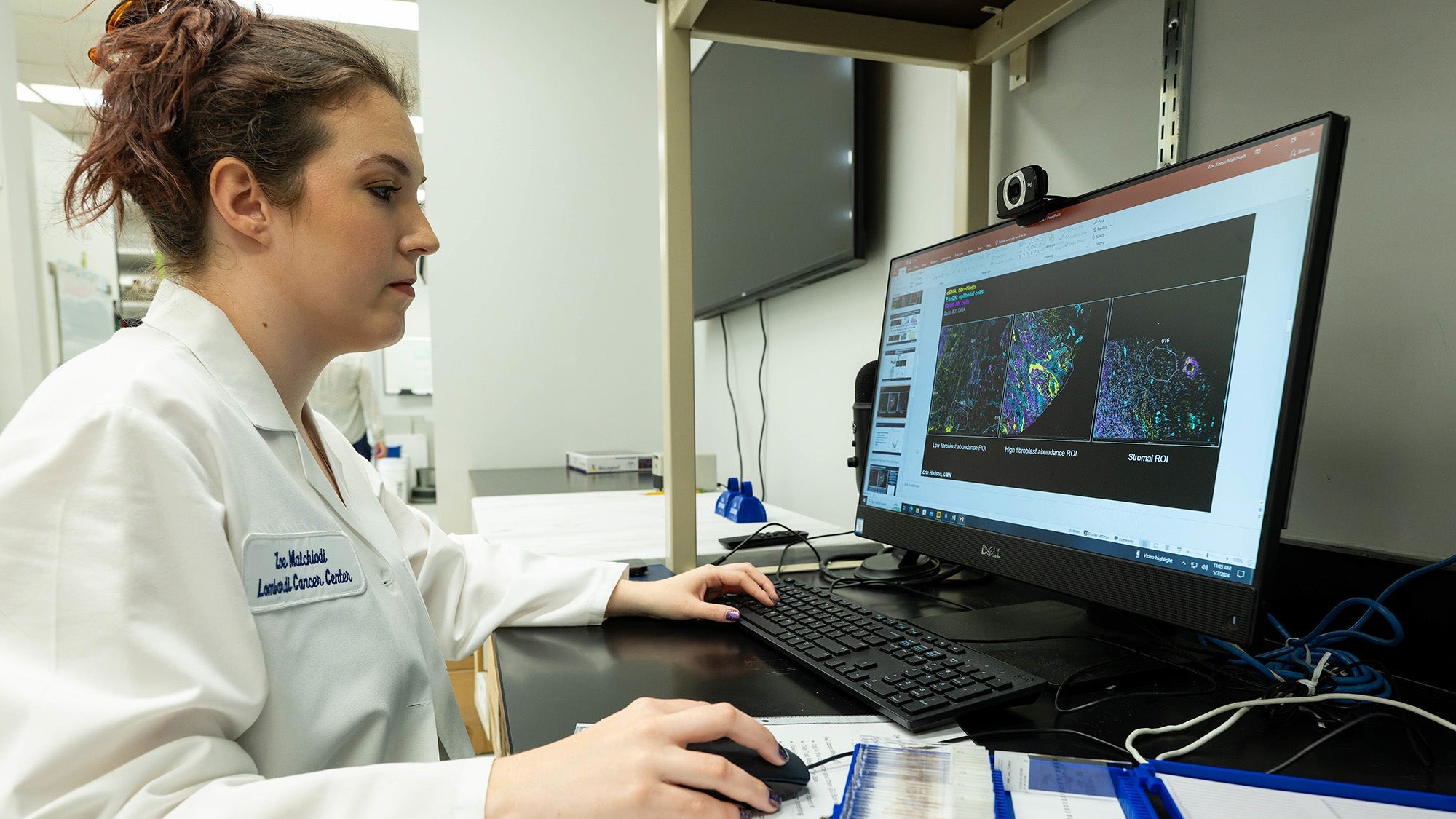 A PhD student in white coat works at a computer