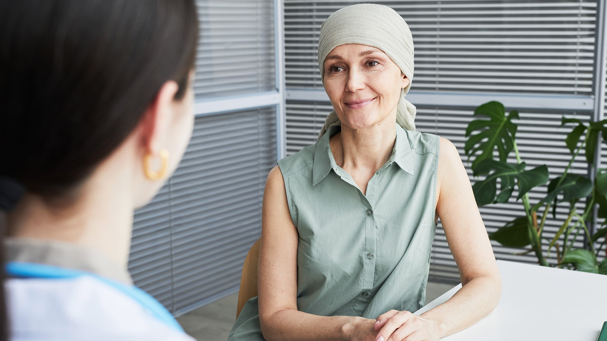 A breast cancer patient wearing a headscarf listens to a medical professional