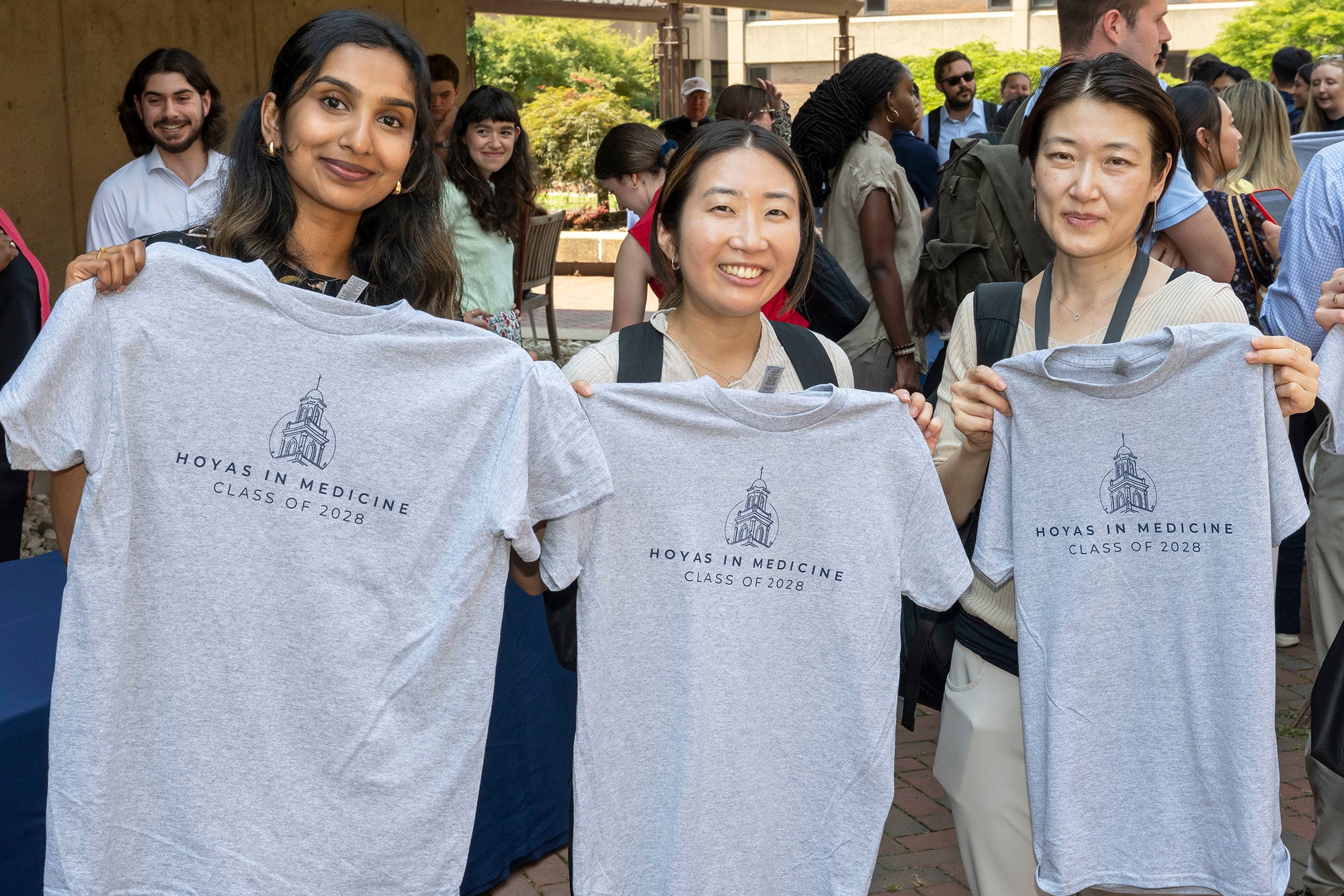 Three medical students hold up T-shirts they received at an event