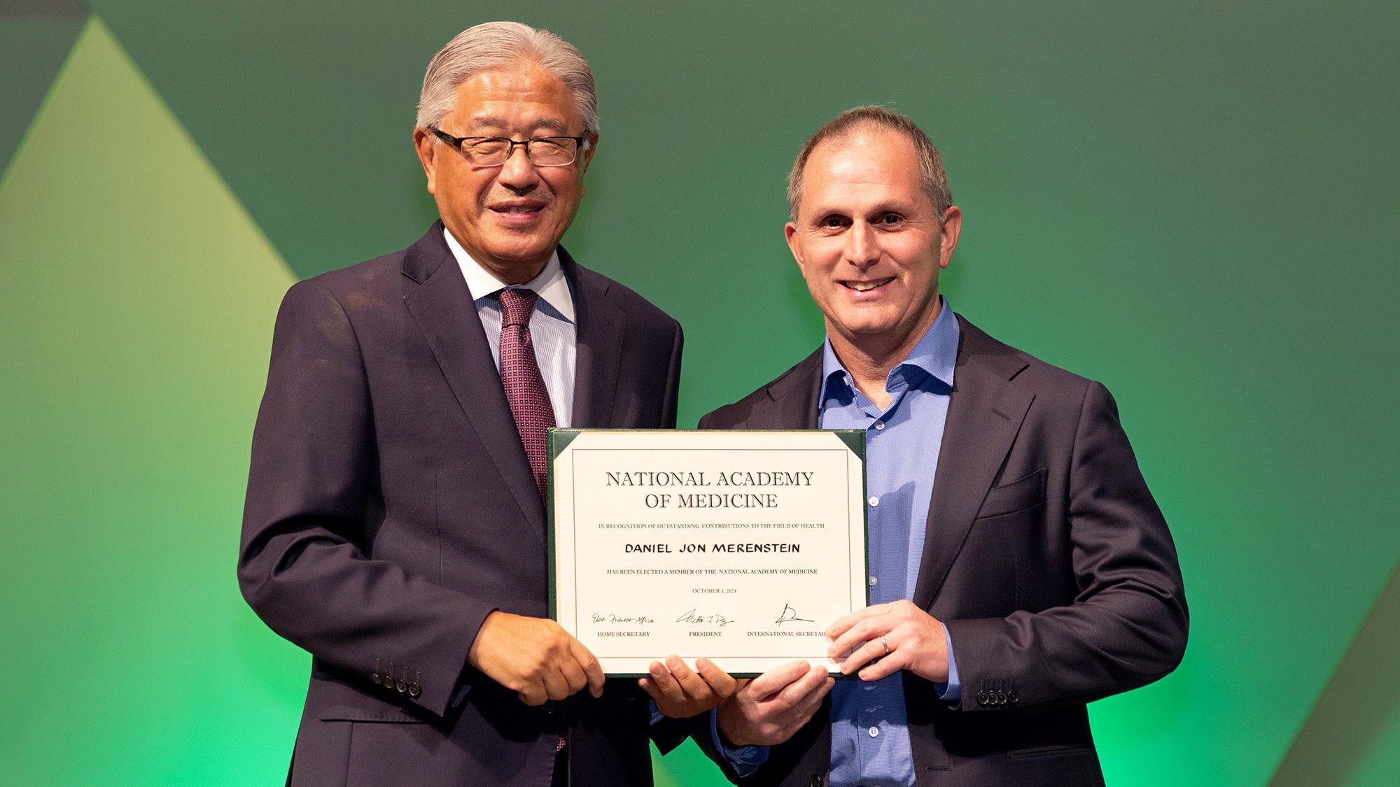 Victor Dzau and Dan Merestein stand with Merenstein's certificate from the National Academy of Medicine