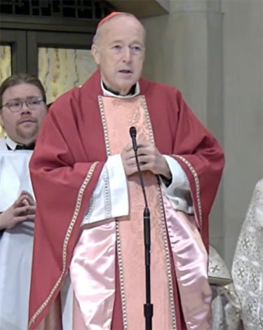 Cardinal McElroy in his vestments speaks into a microphone