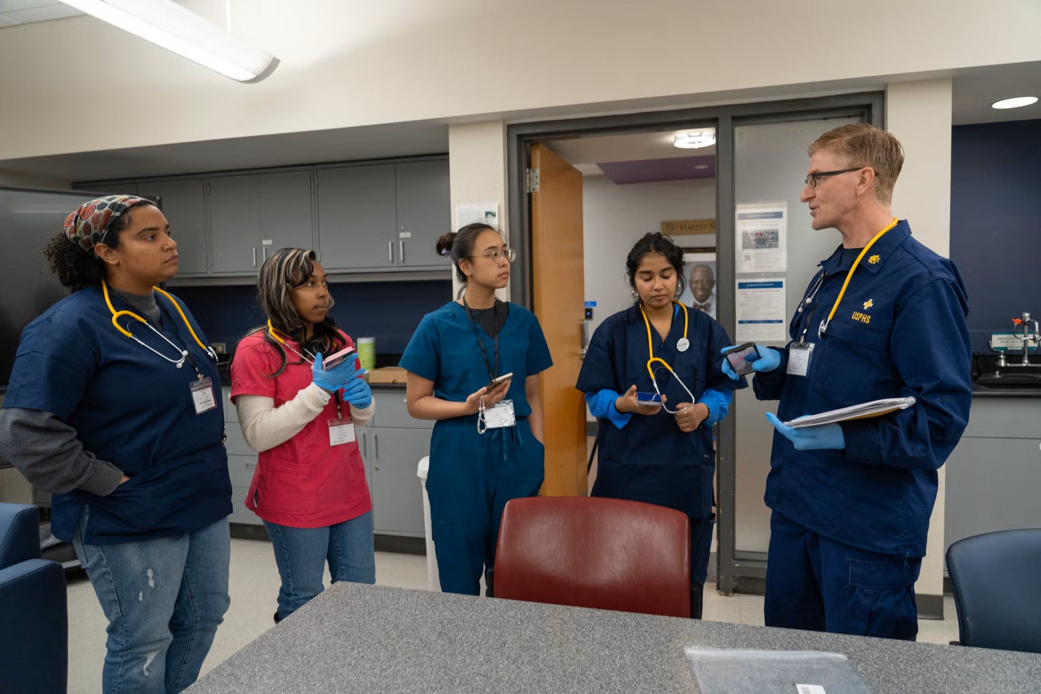 Five people in medical scrubs prepare for the outbreak simulation in a classroom