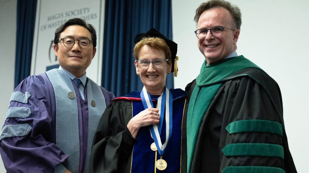 Dr. Song, Dr. Riegel and Dr. Beauchamp stand together wearing academic regalia