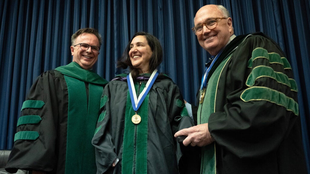 Dr. Beauchamp, Dr. Topal and Dr. Mitchell stand together wearing academic regalia