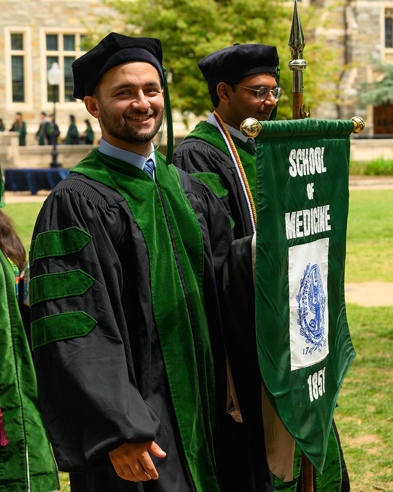 Christopher Guirguis helps carry the School of Medicine banner into Commencement