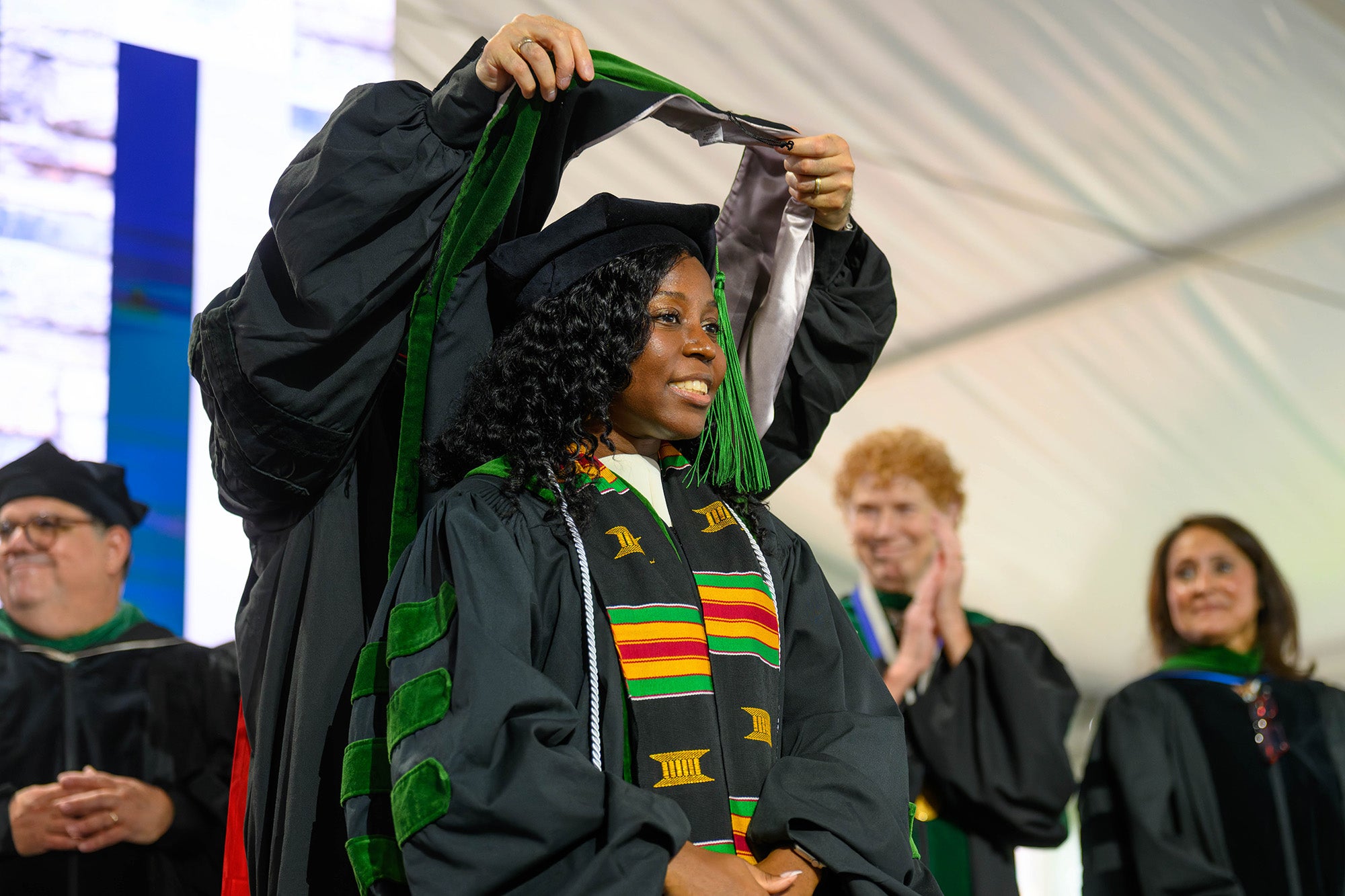 A Black medical graduate receives her hood