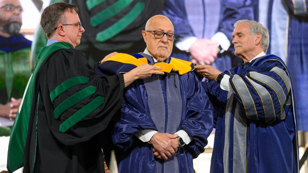 Dr. Beauchamp and Dr. Groves lower the yellow hood over Dr. Pellegrini's head and shoulders