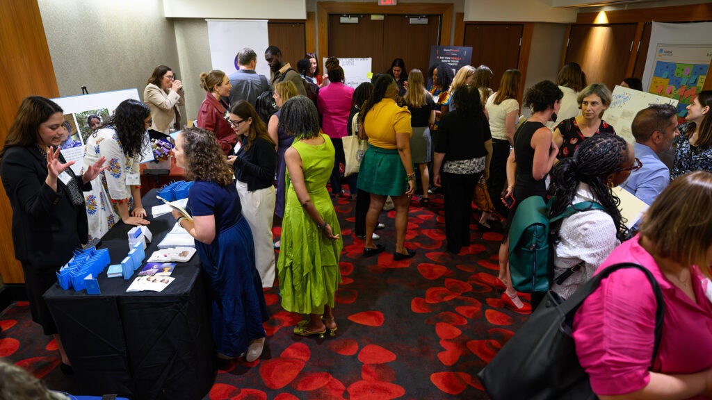 People attending the solutions fair congregate around displays in a room