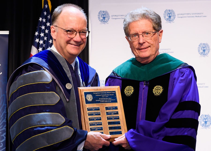 John J. DeGioia and Richard Schlegel with the plaque honoring him at convocation