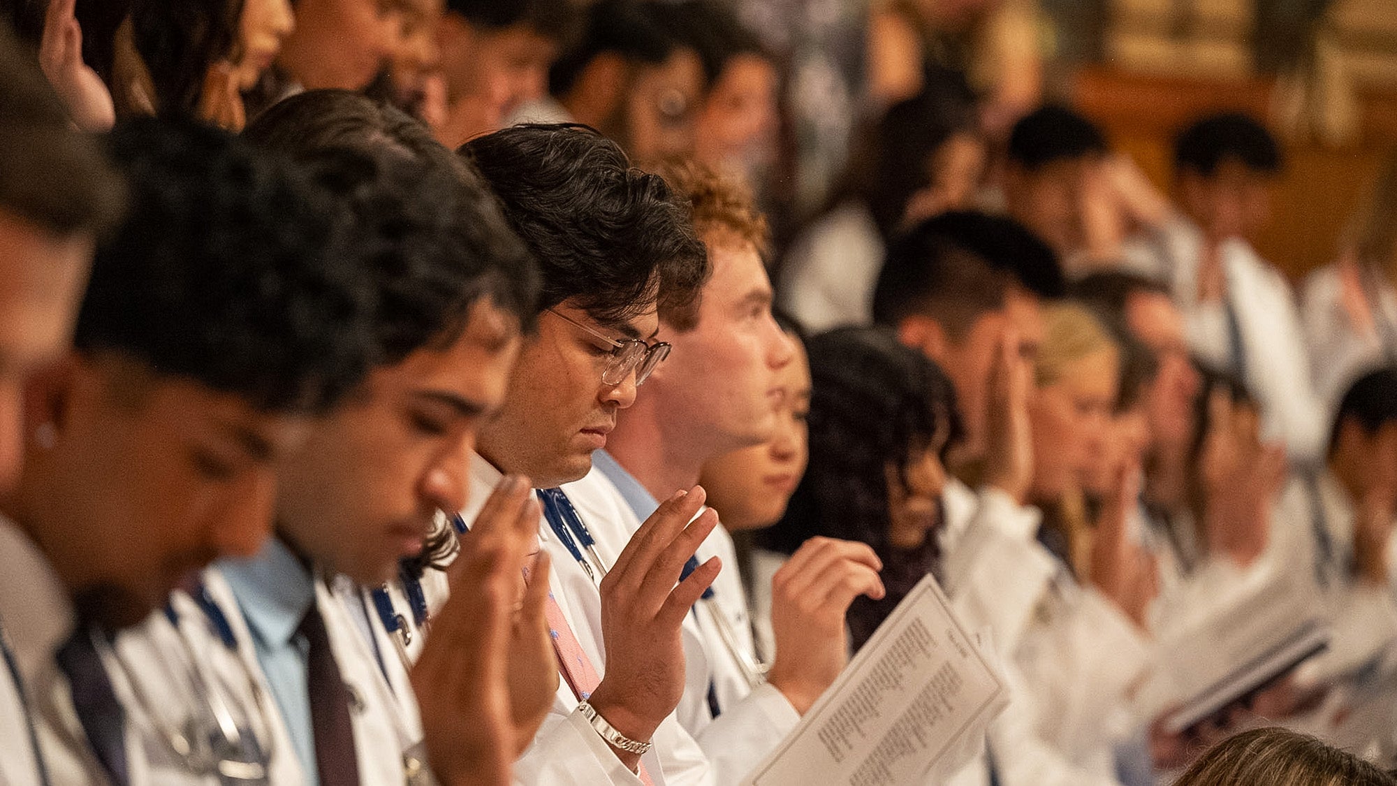 Medical students raise a hand to take the Hippocratic Oath