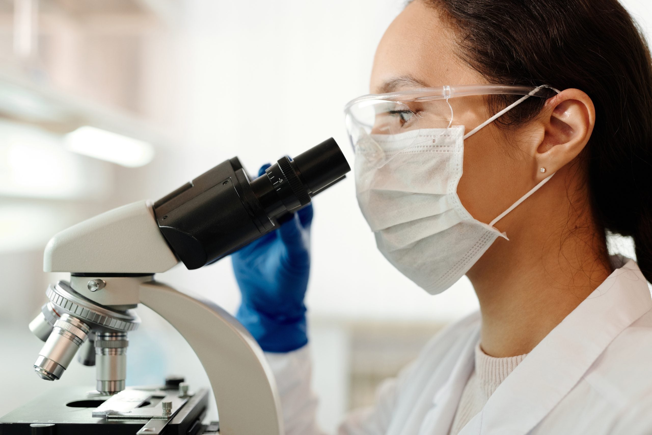 A female researcher looks through a microscope